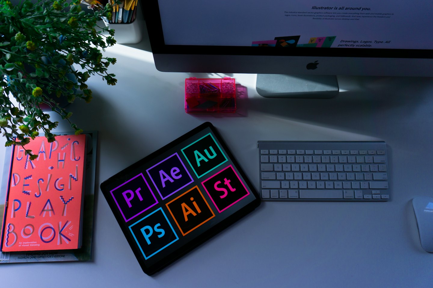 Bilgisayar, tablet ve tasarım araçlarıyla düzenli bir grafik tasarımcı masası.